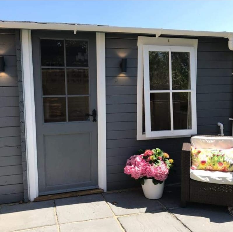 The grey timber Beauty by Laura treatment cabin with flowers by the entrance