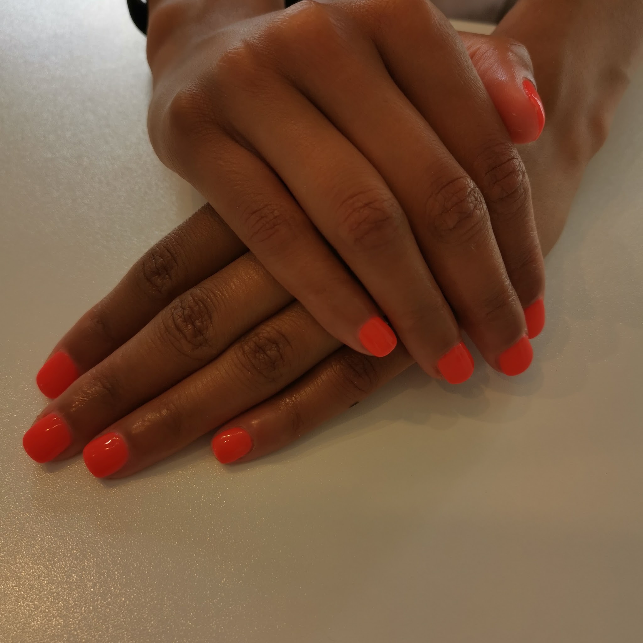 A finished glossy coral manicure by Laura